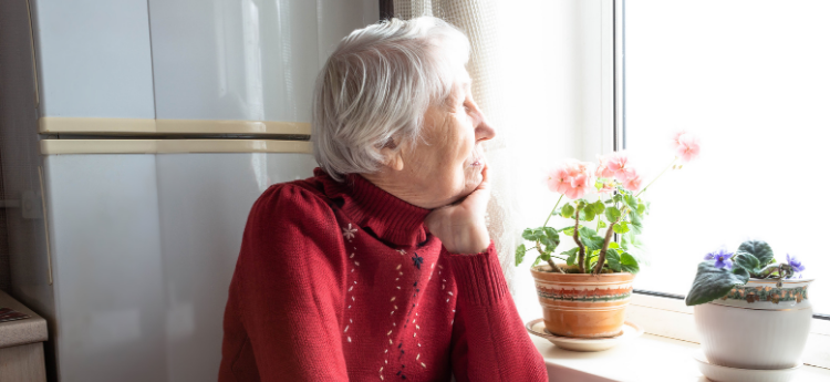Elderly woman staring out a window.